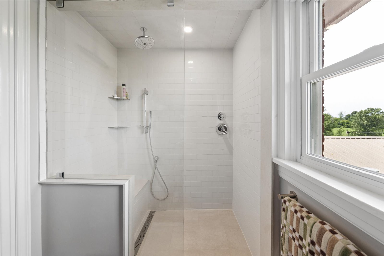 Walk-in tiled shower with rainhead and barn views