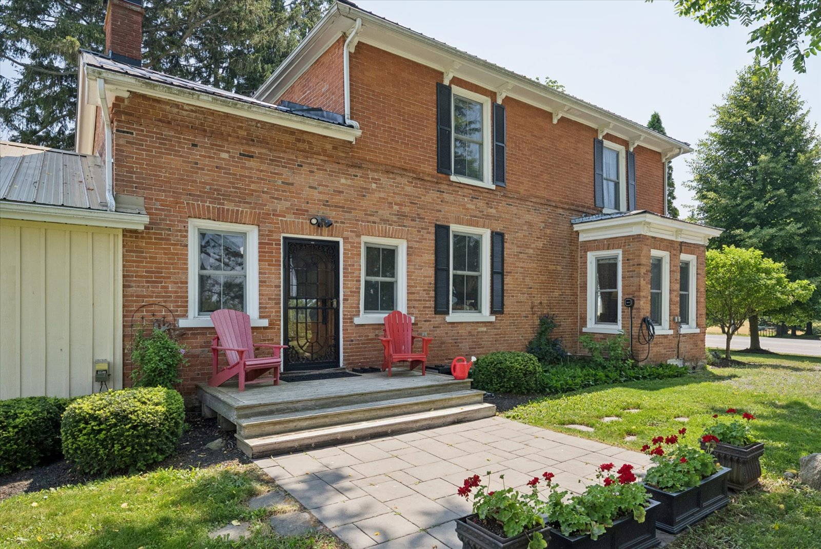 Side entrance with red Muskoka chairs and geraniums